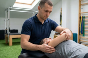 Fisioterapeuta realizando mobilização passiva suave no ombro de paciente em pós-operatório