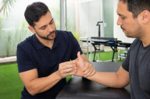 Fisioterapeuta avaliando a base do polegar e a força de pinça de paciente com suspeita de rizartrose em clínica moderna.